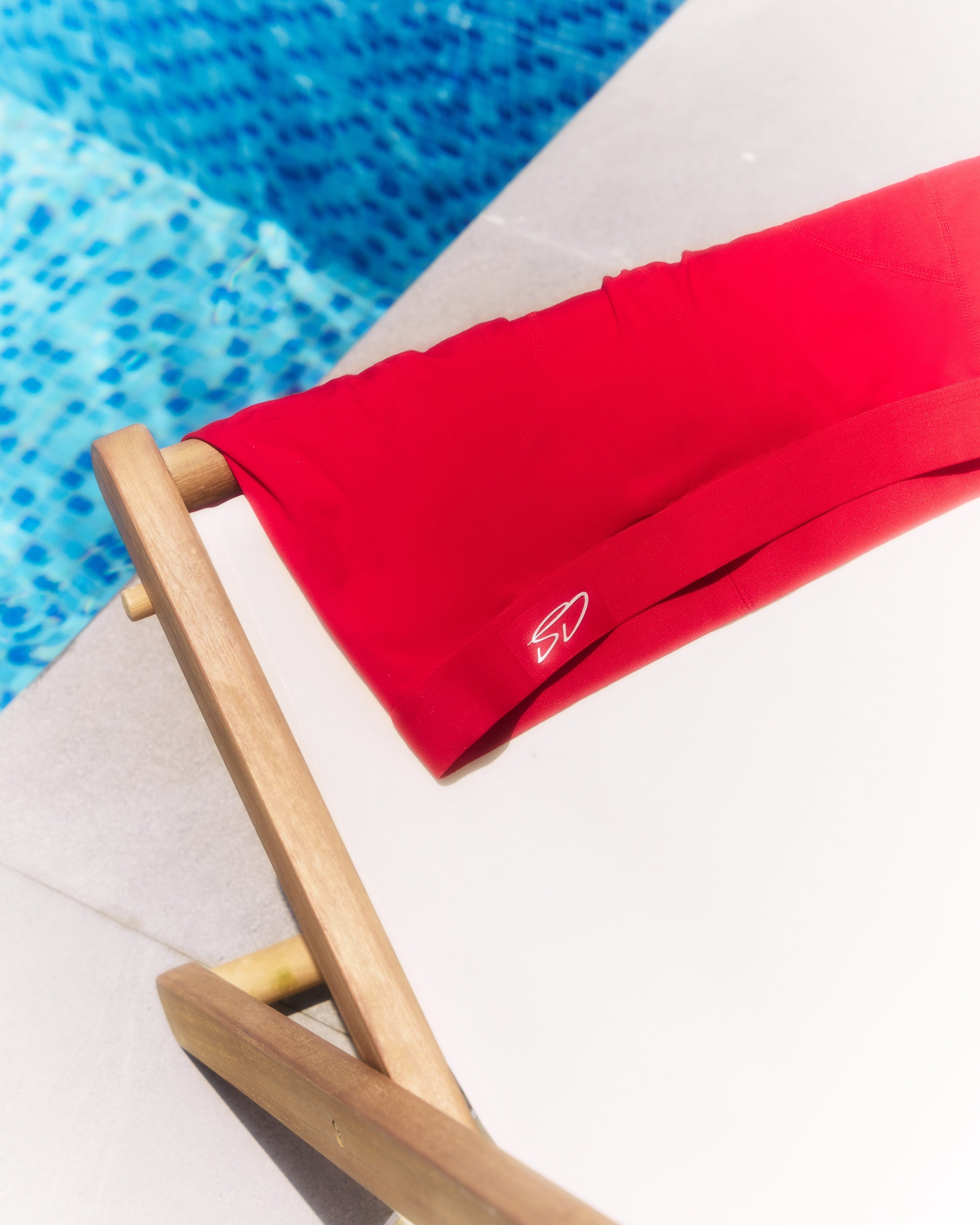 Cottosilk ultra light cotton boxer brief in crimson hanging on a pool chair.
